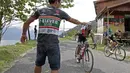 Seorang asisten tim memberikan minum kepada pebalap yang melintas jalur kelok 44  etape ke-4 Tour de Singkarak 2016 di Kabupaten Agam, Sumatera Barart. (Bola.com/NIcklas anoatubun)