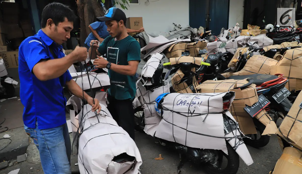 Pekerja membungkus sepeda motor yang akan dikirim di Stasiun Pasar Senen, Jakarta, Selasa (5/6). Jasa pengiriman motor ke daerah meningkat dua kali lipat jelang arus mudik dan Hari Raya Idulfitri 2018. (Liputan6.com/Arya Manggala)