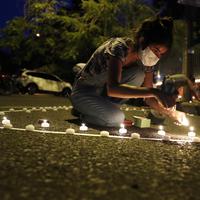 Belen Nunez menyalakan lilin untuk mengenang mereka yang meninggal akibat virus corona di depan Kementerian Kesehatan di Asuncion, Paraguay, Minggu (14/3/2021). Sejuah ini, Paraguay mencatat 3.450 kasus kematian akibat COVID-19. (AP Photo/Jorge Saenz)