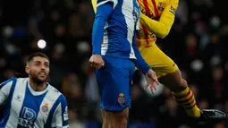 Bek Barcelona, Clement Lenglet melompat saat berebut bola dengan pemain Espanyol Jonathan Calleri pada pekan ke-19 La Liga di RCDE Stadium, Sabtu (4/1/2020). Hampir saja menang, Barcelona harus puas menerima hasil imbang 2-2 atas Espanyol. (AP/Joan Monfort)