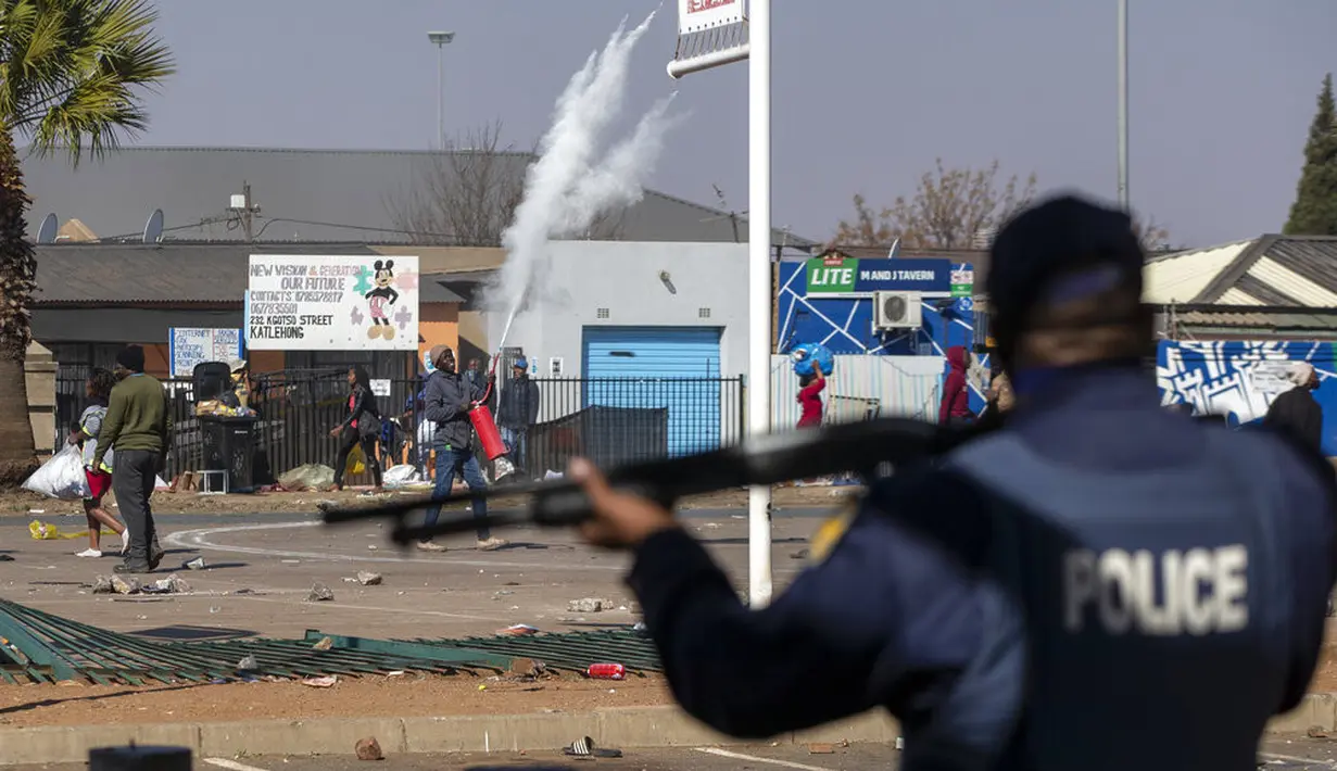 Orang-orang melempari polisi dengan batu ketika mereka mencoba menjarah di Pusat Perbelanjaan Letsoho di Katlehong, sebelah timur Johannesburg, Senin (12/7/2021). Kerusuhan dan penjarahan yang dipicu penahanan mantan Presiden Afrika Selatan Jacob Zuma. (AP/Themba Hadebe)