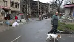 Seorang pria dengan seekor anjing berjalan di jalan yang rusak selama pertempuran sengit di gedung apartemen di daerah yang dikendalikan oleh pasukan separatis yang didukung Rusia di Mariupol, Ukraina, Selasa (19/4/2022).  (AP Photo/Alexei Alexandrov)