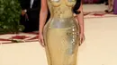 Kim Kardashian cantik banget dengan gaun Versace berwarna emas ditambah hiasan salib. (Getty Images/Cosmopolitan)