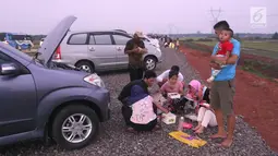 Pemudik menyantap hidangan berbuka puasa di pinggir Tol Fungsional Pemalang-Batang, Jawa Tengah, Minggu (10/6). Mereka memanfaatkan waktu istirahat di pinggir tol yang belum rampung dibangun. (Liputan6.com/Arya Manggala)