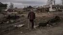 Seorang warga berdiri di samping bagian tank Rusia yang hancur di kota Trostsyanets, Ukraina, Senin, 28 Maret 2022. Trostsyanets baru-baru ini direbut kembali oleh pasukan Ukraina setelah dikuasai oleh Rusia sejak awal perang. (AP Photo/Felipe Dana)
