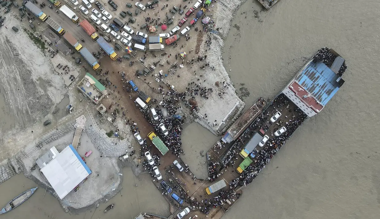 Foto udara yang diambil pada 27 Juni 2021 ini memperlihatkan penumpang naik kapal feri jelang pengetatan lockdown, Munshiganj, Bangladesh. Pembatasan aktivitas dan pergerakan sebenarnya telah dilakukan sejak pertengahan April karena kasus dan kematian terkait COVID-19 melonjak. (Munir Uz zaman/AFP)