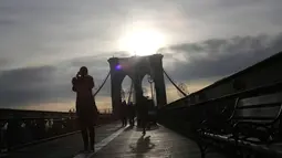Seorang wanita mengambil foto saat berada di Jembatan Brooklyn, New York City, 3 Desember 2018. Jembatan paling legendaris di kota New York itu memiliki fitur arsitektur yang sangat ikonik dan telah diakui dengan banyaknya penghargaan. (AP/Wong Maye-E)
