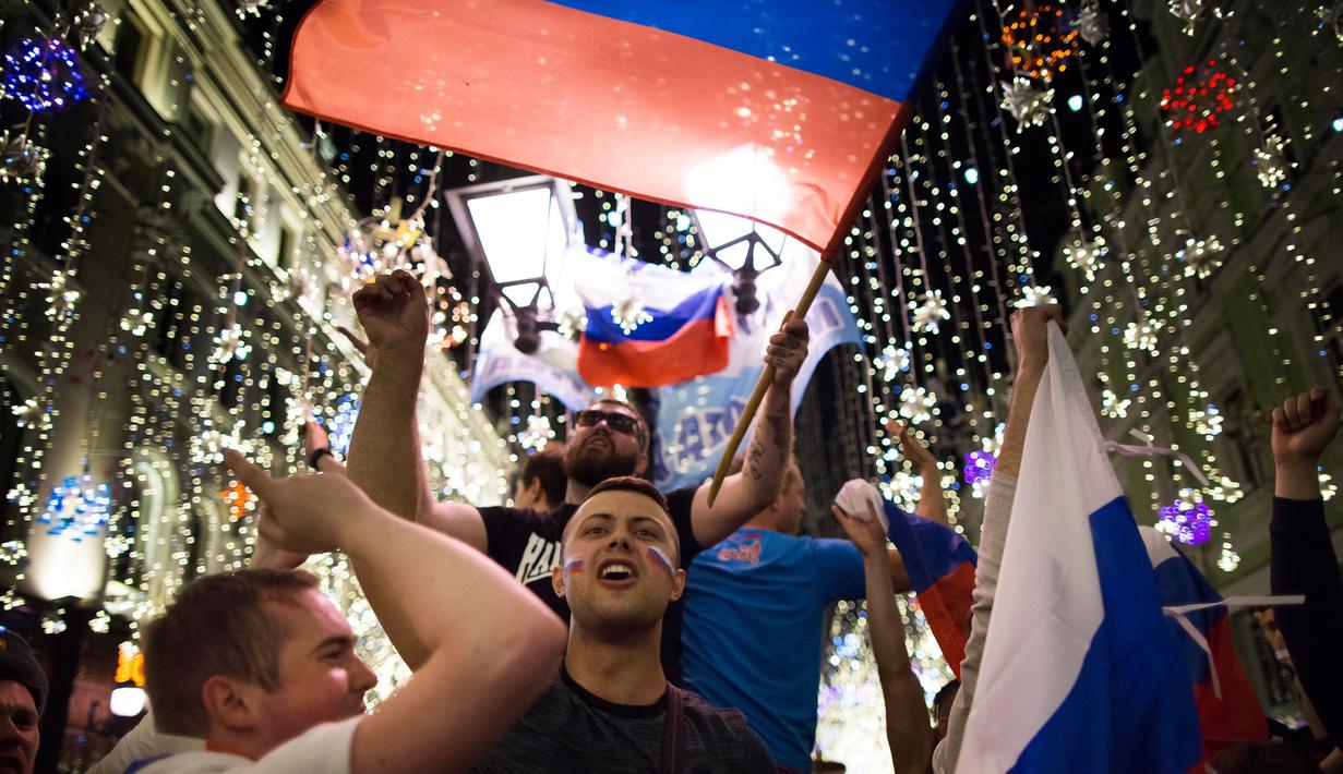 Suporter timnas Rusia merayakan kemenangan atas Mesir pada putaran kedua pertandingan grup A Piala Dunia di Moskow, Rabu (20/6). Tuan rumah Piala Dunia, Rusia menang 3-1 dan kian berpeluang lolos ke 16 besar. (AP/Alexander Zemlianichenko)