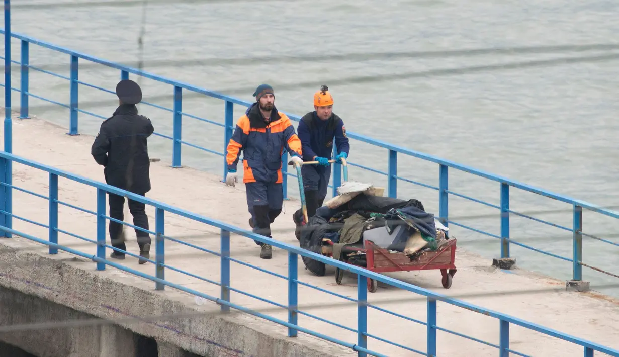 Petugas Kementerian Pertahanan Rusia mendorong gerobak dengan membawa kantong plastik di dermaga Laut Hitam di pinggiran Sochi, Rusia (25/12). Mereka menuju Suriah untuk ikut serta dalam penampilan tahun baru bagi tentara Rusia. (REUTERS/Yevgeny Reutov) 