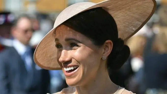 Meghan Markle menghadiri pesta kebun Istana Buckingham di London, Selasa (22/5). Royal hat senada dari Philip Treacy juga tak kalah menjadikan Meghan Markle tampil mengagumkan. (Dominic Lipinski/Pool Photo via AP)