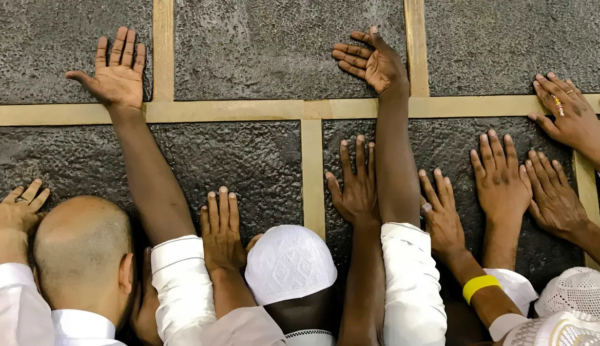Umat muslim memagang bangunan Kakbah di Masjidil Haram, Mekah, Arab Saudi, Jumat (17/8). Dalam ritual ibadah haji umat muslim diharuskan tawaf atau berputar mengelilingi Kakbah berlawanan arah jarum jam. (AP Photo/ Dar Yasin)