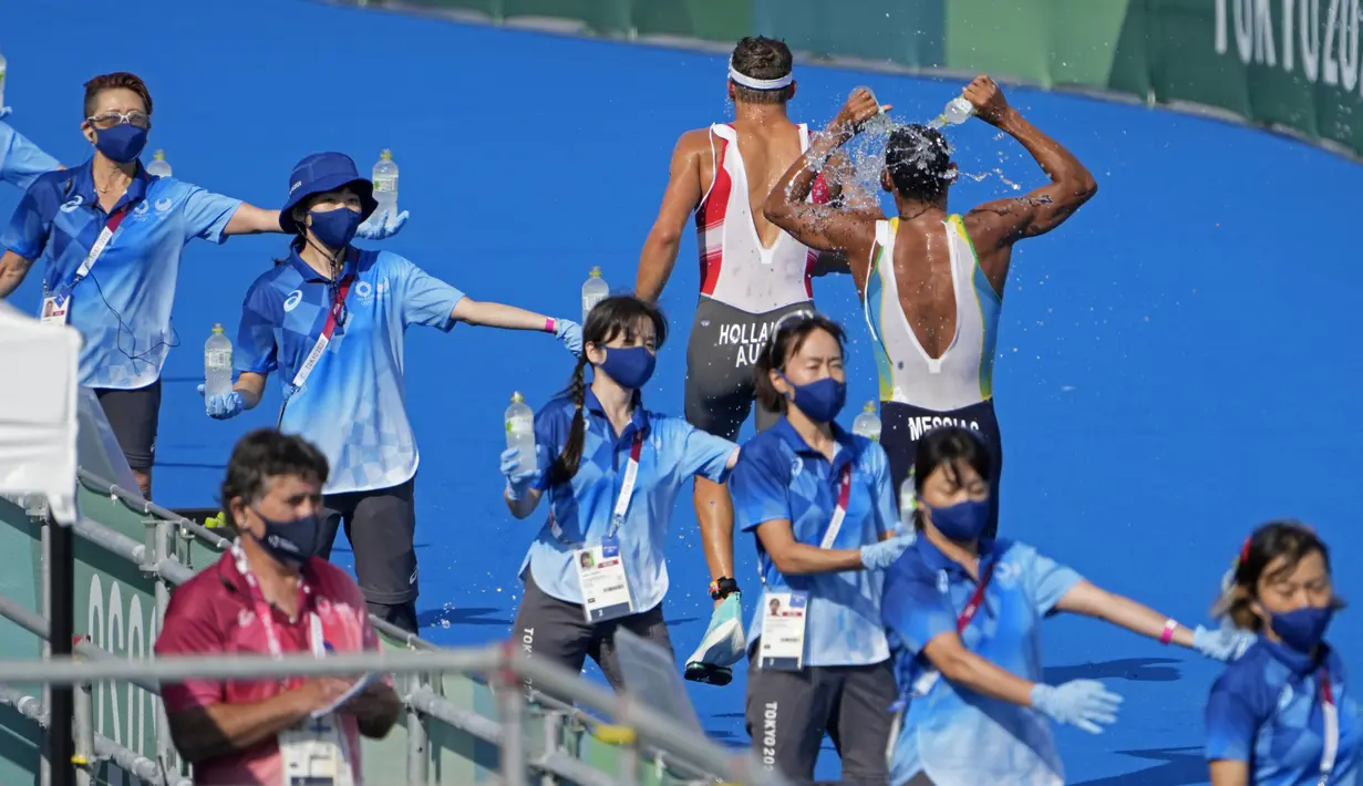 Lukas Hollaus dari Austria dan Manoel Messias dari tim Brasil mengambil air yang diberikan sukarelawan selama triathlon individu putra Olimpiade Tokyo 2020, pada 26 Juli 2021. Relawan merupakan salah satu kunci suksesnya suatu perhelatan, tak terkecuali Olimpiade Tokyo 2020 ini. (AP/Jae C.Hong)