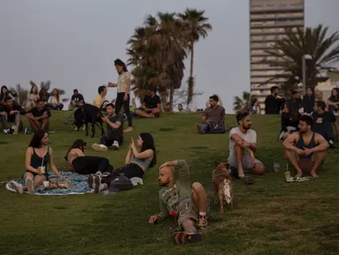 Orang-orang tanpa masker menyaksikan matahari terbenam, di Tel Aviv, Minggu (18/4/2021). Israel mencabut aturan wajib masker di ruang publik luar ruangan dan membuka kembali sekolah sepenuhnya dalam upaya menuju normalisasi setelah kampanye vaksinasi Covid-19 berjalan sukses. (AP Photo/Oded Balilty)