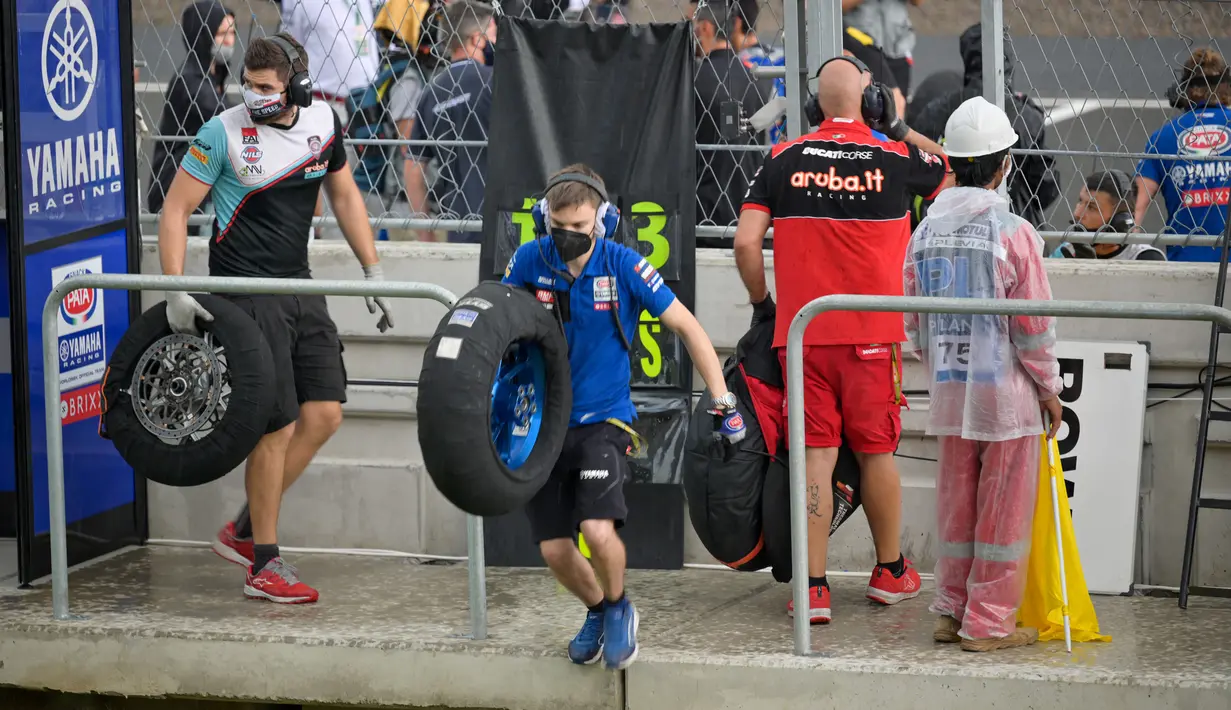 Seorang kru membawa ban yang basah akibat hujan lebat sebelum Race 2 WSBK Mandalika 2021 di Pertamina Mandalika International Street Circuit, Lombok, Nusa Tenggara Barat, Minggu (21/11/2021). Balapan dilanjutkan pukul 15.30 WIB atau 16.30 Wita dan hanya digelar 12 lap. (BAY ISMOYO/AFP)