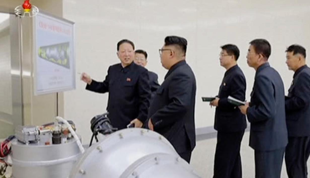 Kim Jong-un berbincang dengan para peneliti saat meninjau pembuatan bom hidrogen pada 3 September 2017. Bom ini diklaim berkekuatan hingga ratusan kiloton ini dibuat dengan berbagai komponen produksi dalam negeri. (KRT via AP Video)
