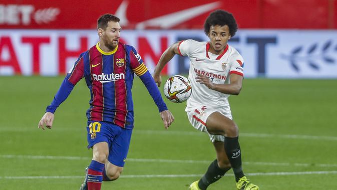 Pemain Barcelona Lionel Messi memperebutkan bola dengan pemain Sevilla Jules Kounde pada pertandingan semifinal Copa del Rey Spanyol di stadion Ramon Sanchez Pizjuan di Seville, Spanyol, Rabu, 10 Februari 2021. (Foto AP / Angel Fernandez)