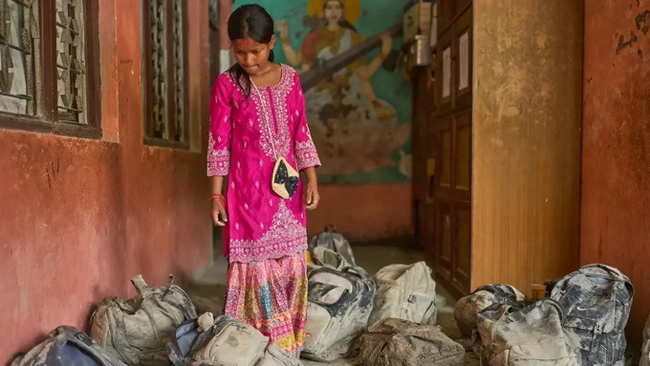 Seorang siswi mencari tas sekolahnya di antara tumpukan tas yang ditemukan dari lumpur sisa banjir bandang di Shree Bagheswori Madhyamik School, Galchhi, Distrik Dhading, Nepal, Minggu (30/8/2026).