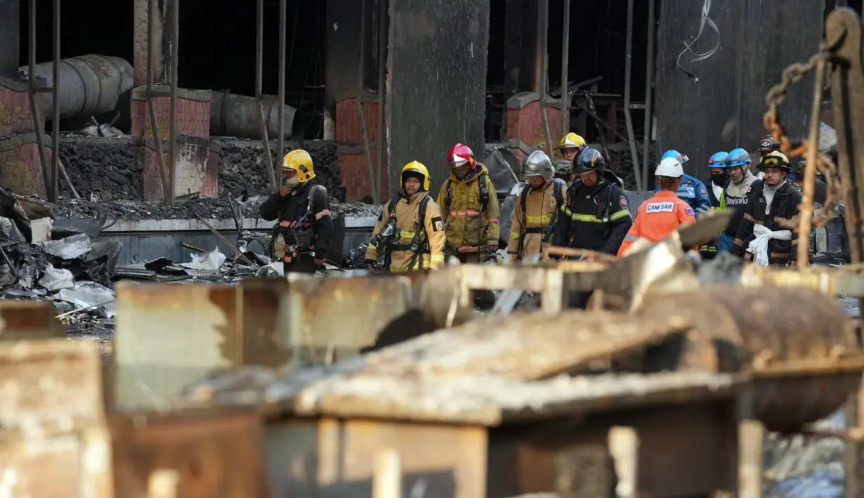 Pakar penyelamat Kamboja dan Thailand berjalan melalui reruntuhan bangunan untuk operasi pencarian di lokasi kebakaran besar kasino hotel Kamboja di Poipet, Kamboja, Jumat (30/12/2022). Kebakaran terjadi pada Rabu tengah malam di Hotel Grand Diamond City di Poipet, sebuah kota yang berbatasan dengan Thailand. (AP Photo/Heng Sinith)