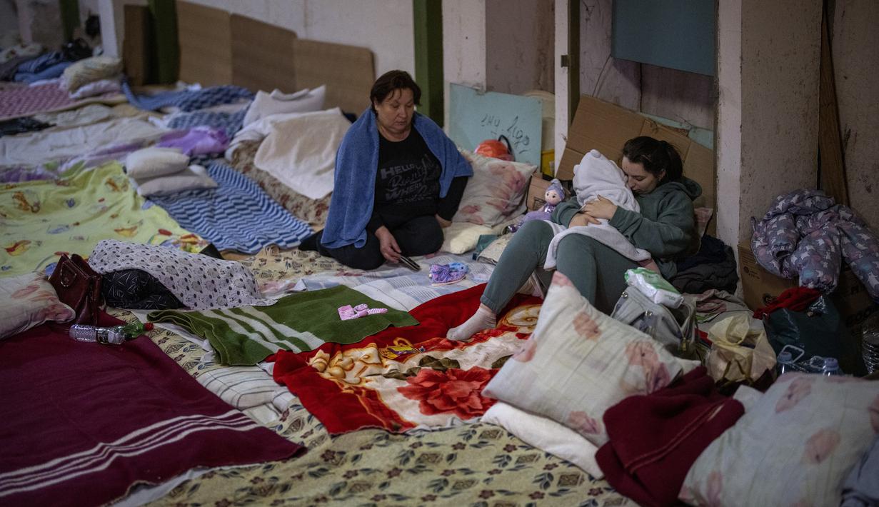 Seorang perempuan memeluk bayinya yang baru lahir di lengannya di ruang bawah tanah yang digunakan sebagai tempat perlindungan bom di rumah sakit anak Okhmadet di pusat Kiev, Ukraina, Senin (28/2/2022). Hingga kini invasi militer Rusia ke Ukraina terus berlanjut. (AP Photo/Emilio Morenatti)