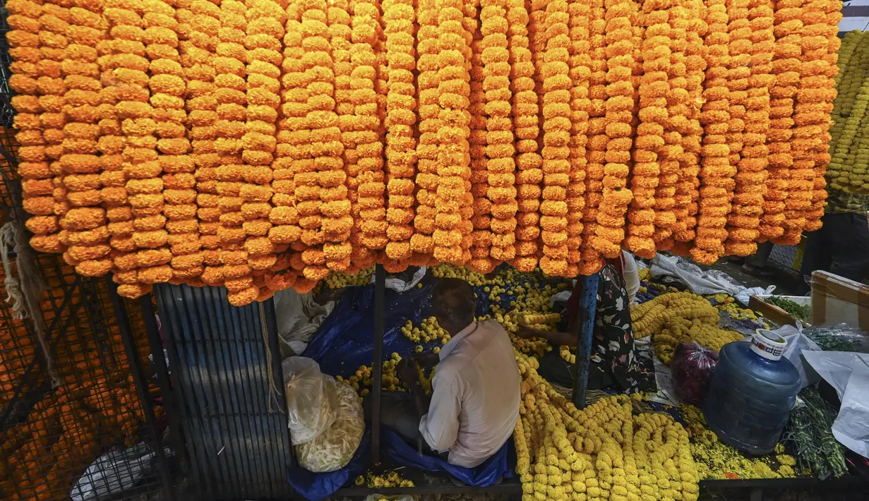 Seorang pria membuat karangan bunga jelang Festival Diwali di pasar bunga New Delhi, India, Minggu (31/10/2021). Festival Diwali atau Festival Cahaya dalam agama Hindu melambangkan kemenangan baik atas buruk. (Money SHARMA/AFP)
