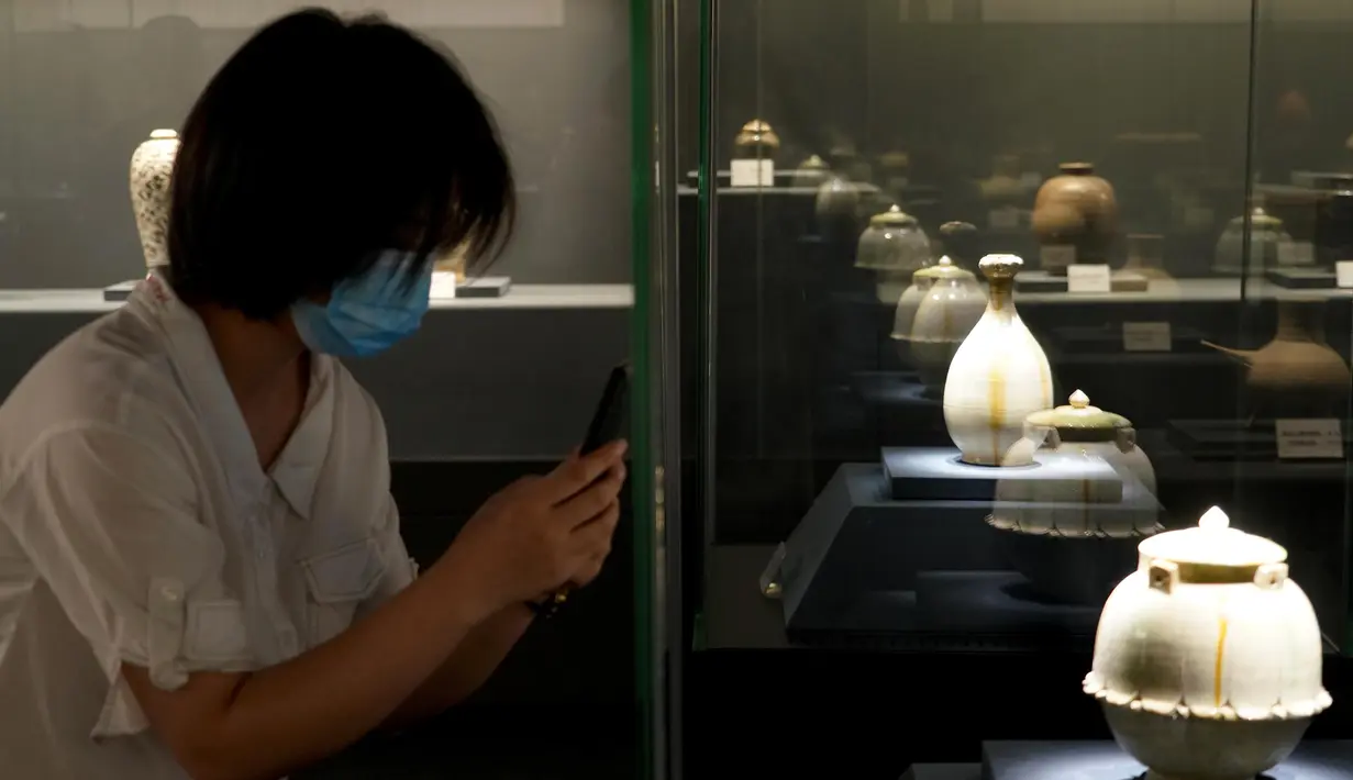 Pengunjung memotret benda yang dipajang dalam pameran keramik di Zhengzhou, Provinsi Henan, China, 25 Agustus 2020. Pameran keramik tersebut dimulai di Zhengzhou pada Selasa (25/8) dengan menampilkan 100 lebih benda dari zaman kuno yang ditemukan di sepanjang cekungan Sungai Kuning. (Xinhua/Li An)
