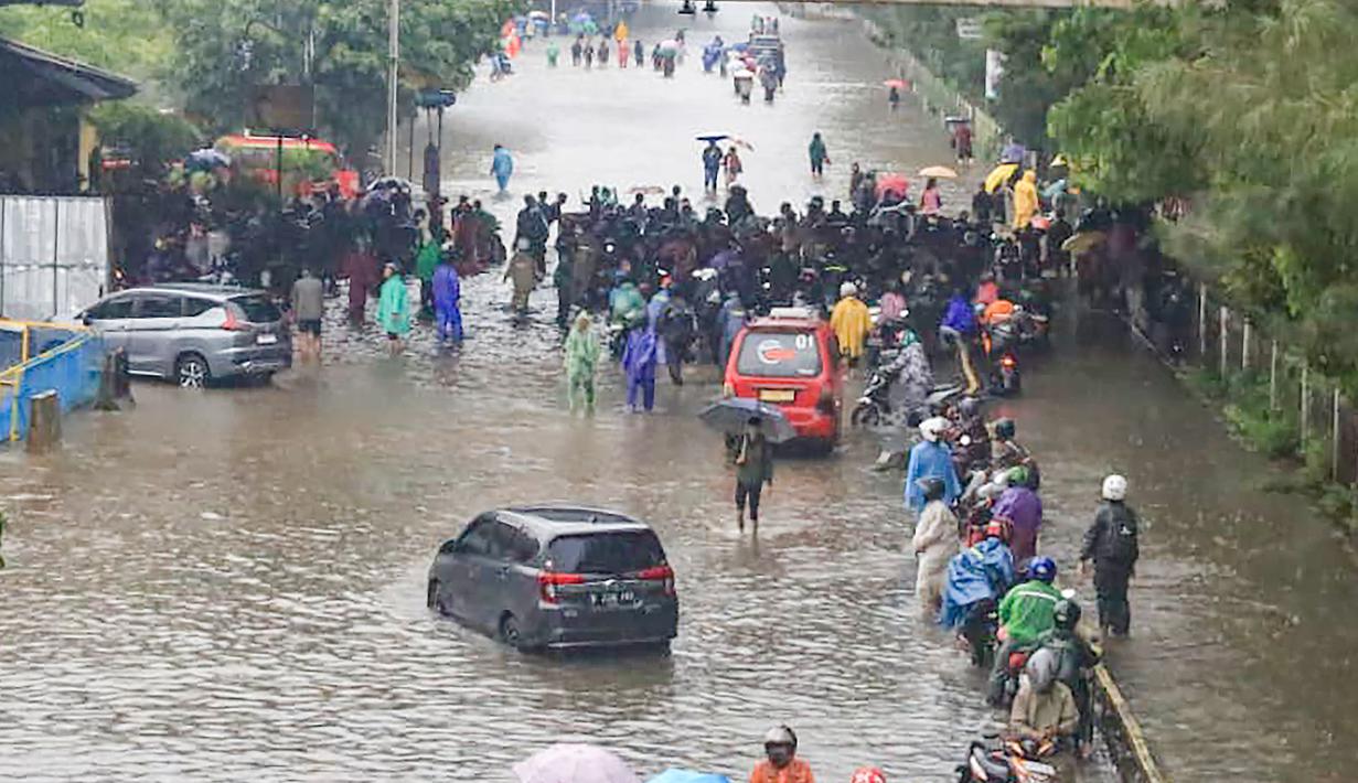 Wilayah terdampak tersebar di Jakarta Selatan dan Jakarta Utara. Di Jakarta Selatan, banjir merendam delapan RT, sementara dua RT lainnya berada di Jakarta Utara. Tampak dalam foto, pengendara dan pejalan kaki melintasi banjir yang menggenangi Jalan Jembatan Tiga Raya, Jakarta Utara, Senin (12/1/2026). (merdeka.com/Arie Basuki)