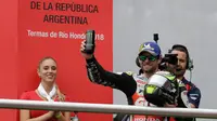Pembalap LCR Honda, Cal Crutchlow merayakan kemenangannya pada balapan MotoGP Argentina di atas podium Sirkuit Termas de Rio Hondo, Minggu (8/4). Kemenangan ini menempatkan Crutchlow di puncak klasemen sementara dengan poin 38. (AP/Natacha Pisarenko)