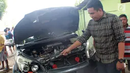 Seorang pria menunjukkan mobil yang rusak usai tertimpa pohon berumur puluhan tahun di Jalan Trans Sulawesi, Limboto, Gorontalo, Senin, (21/1). Tidak ada korban jiwa dalam kejadian tersebut. (Liputan6.com/Arfandi Ibrahim)