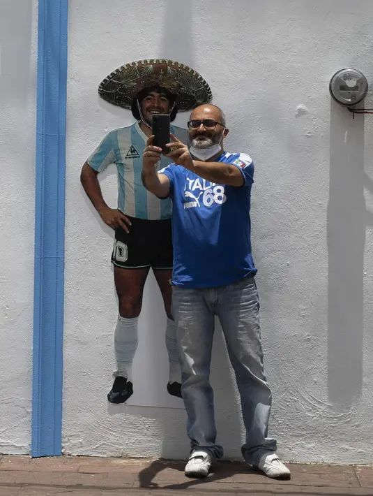 Seorang turis berfoto selfie di depan Gereja Maradona di San Andres Cholula, negara bagian Puebla, Meksiko, Minggu (18/7/2021). Di bagian depan gereja terdapat foto Maradona mengenakan kostum timnas Argentina dan topi charro. (AP Photo/Marco Ugarte)