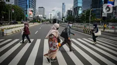 Sejumlah pekerja berjalan melintas pelican cross di kawasan Jalan Sudirman, Jakarta, Selasa (2/11/2021). Sektor non-esensial kini boleh mempekerjakan hingga 75 persen karyawannya dari kantor. Sebelumnya, angka ini dibatasi hingga 50 persen. (Liputan6.com/Faizal Fanani)