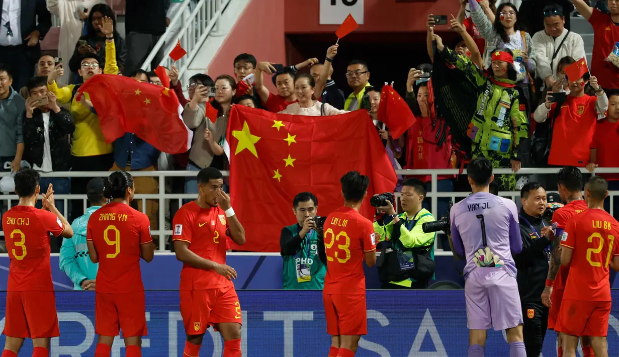 Suporter melambaikan bendera negara mereka saat para pemain China memberi hormat setelah berakhirnya pertandingan sepak bola Grup A Piala Asia AFC Qatar 2023 melawan Tajikistan di Stadion Abdullah bin Khalifa di Doha pada 13 Januari 2024. (KARIM JAAFAR/AFP)