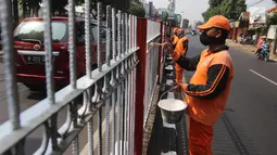 Petugas PPSU Kelurahan Kramat Jati mengecat ulang pagar pembatas Jalan Raya Bogor, Jakarta, Selasa (17/7). Pengecatan sebagai upaya perawatan berkala terhadap sarana dan prasarana yang sudah mulai kehilangan fungsi atau rusak. (Liputan6.com/Arya Manggala)