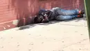 Seorang pria tertidur usai menghisap ganja sintetis di pinggir jalan East Harlem, New York (5/8/2015). Ganja sintetis memiliki efek yang buruk bagi penggunanya karena merupakan senyawa kimia yang berbahaya. (AFP PHOTO/SPENCER PLATT)