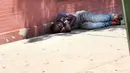 Seorang pria tertidur usai menghisap ganja sintetis di pinggir jalan East Harlem, New York (5/8/2015). Ganja sintetis memiliki efek yang buruk bagi penggunanya karena merupakan senyawa kimia yang berbahaya. (AFP PHOTO/SPENCER PLATT)