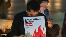 Sejumlah poster yang dibawa simpatisan masyarakat turut mewarnai aksi solidaritas dan doa bersama untuk korban kebakaran hutan dan lahan (karhutla) di Tugu Proklamasi, Jakarta, Senin malam (19/10/2026). (KLY/Budy Santoso)