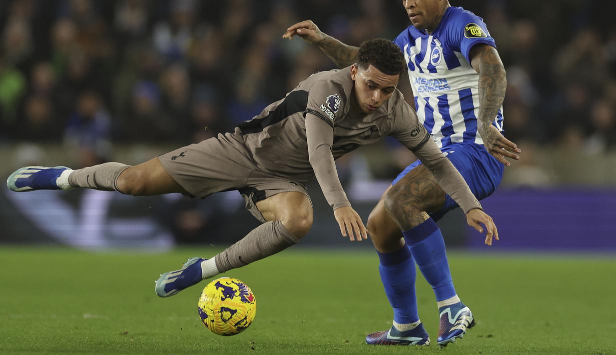 Pemain Tottenham Hotspur, Brennan Johnson (kiri) terjatuh saat berebut bola dengan pemain Brighton, Igor Julio pada laga lanjutan Liga Inggris 2023/2024 di American Express Community Stadium, Brighton, Inggris, Jumat (29/12/2023) dini hari WIB. (AP Photo/Ian Walton)