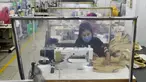 Para buruh bekerja pada stasiun mereka yang dipisahkan oleh sekat sebagai tindakan pencegahan terhadap penularan virus corona COVID-19 di pabrik garmen Civil Engineers Limited, Dhaka, Bangladesh, 17 Agustus 2021. (Munir UZZAMAN/AFP)