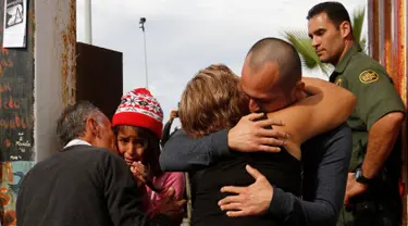 Seorang pria memeluk keluarganya di depan gerbang perbatasan Meksiko dan Amerika Serikat, Tijuana, Meksiko (19/11). Untuk memperingati Hari Anak Sedunia, petugas perbatasan membolehkan imigran Meksiko bertemu dengan keluarganya. (Reuters/Jorge Duenes)