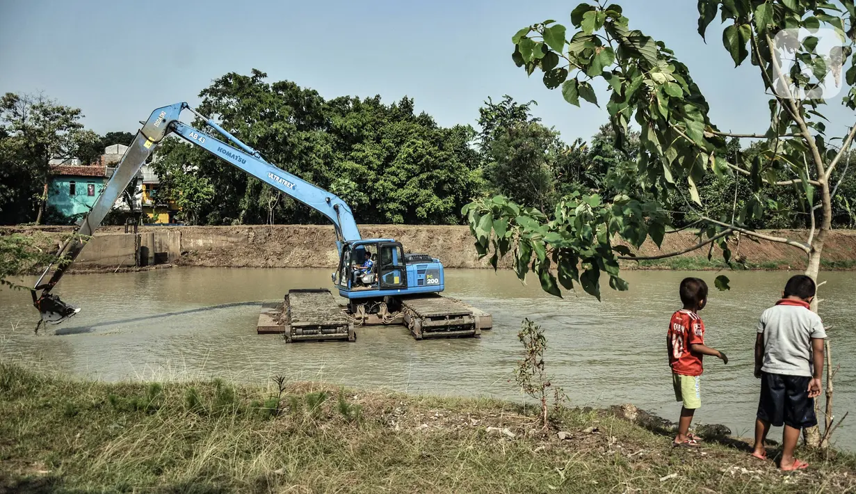 Anak-anak bermain dekat pengerukan lumpur di Waduk Setu, Cipayung, Jakarta, Rabu (28/7/2021). Pengerukan lumpur ini dilakukan untuk mencegah terjadinya banjir saat musim hujan. (merdeka.com/Iqbal S. Nugroho)