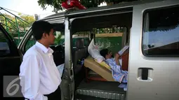 Petugas mengawasi siswa SMP N 2 Pakem ,Fitrian saat mengerjakan soal Ujian Nasional di halaman SMP N 2 Pakem, Sleman, (10/5). Akibat kecelakaan,Fitrian terpaksa melaksanakan UN di dalam mobil ambulans . (Liputan6.com/Boy Harjanto)