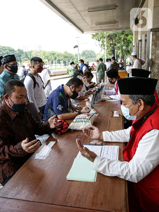 Amil zakat mendoakan umat muslim yang membayar zakat fitrah di Masjid Istiqlal, Jakarta, Jumat (7/5/2021). Panitia Zakat Masjid Istiqlal mulai membuka layanan pembayaran zakat fitrah dengan pembayaran senilai Rp 50 ribu atau 3,5 liter beras. (Liputan6.com/Faizal Fanani)