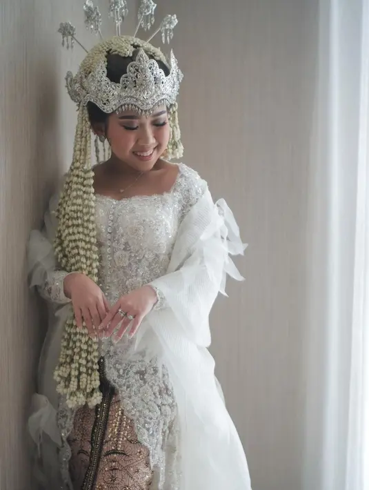 Di momen pernikahan,  Kiky Saputri tampil anggun dengan balutan kebaya Sunda berwarna putih. Kebaya rancangan Didiet Maulana ini dipermanis dengan modifikasi organza. [Foto: IG/@cappiophoto]