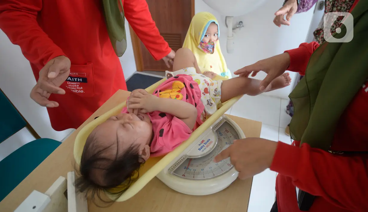 Kader Posyandu menimbang berat badan anak yang akan divaksin di RW 09, Pondok Benda, Tangerang Selatan, Senin (14/12/2020). Program rutin pemerintah setiap bulan ini digelar lewat posyandu dengan penyuluhan dan perawatan anak agar tumbuh kembangnya sehat. (merdeka.com/Dwi Narwoko)