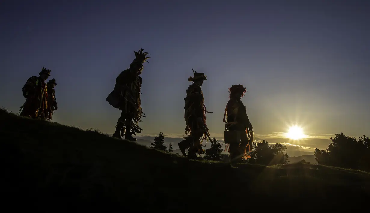 Anggota Powderkeg Morris Dancers turun dari Windgather Rocks saat matahari terbit usai melakukan festival Celtic kuno di High Peak di Derbyshire (1/5). (AFP Photo/Lindsey Parnaby)