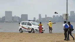 Mobil polisi terparkir di pantai Girgaum Chowpatty saat awan gelap menyelimuti langit Mumbai (12/6/2019). Badai siklon vayu melesat ke arah barat India telah diperkuat dengan hembusan angin hingga 170 kilometer per jam (105 mph) yang  akan menerjang pada 13 Juni 2019. (AFP Photo/Punit Paranjpe)