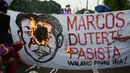 Demonstran membakar spanduk yang bergambar wajah Ferdinand Marcos dan Presiden Rodrigo Duterte saat ulang tahun Ferdinand Marcos ke-100 di Manila (11/9). (AFP Photo/Ted Aljibe)
