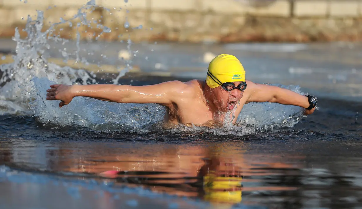 Seorang pria berenang di danau yang sebagaian beku dengan es saat suhu minus 20 derajat Celcius di Shenyang di provinsi Liaoning timur laut China (10/12). (AFP Photo/Str/China Out)