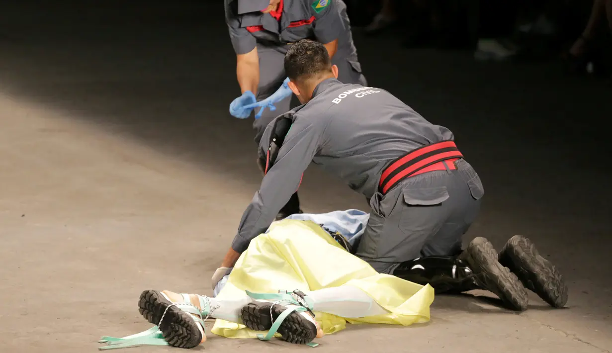 Petugas medis berusaha menyelamatkan model Tales Cotta saat terjatuh di catwalk Sao Paulo Fashion Week, Sao Paulo, Brasil, 27 April 2019. Model berusia 26 tahun tersebut tiba-tiba ambruk dan tidak bangkit lagi. (REUTERS/Leco Viana)