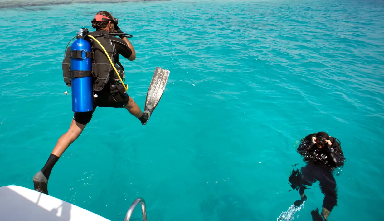 Instruktur selam Arab Saudi, Nouf Alosaimi bersama instruktur selam Mesir, Tamer Nasr melompat ke Laut Merah dekat King Abdullah Economic City. Pesona keindahan Laut Merah memikat pengunjung dari seluruh dunia. (AP Photo/Amr Nabil)