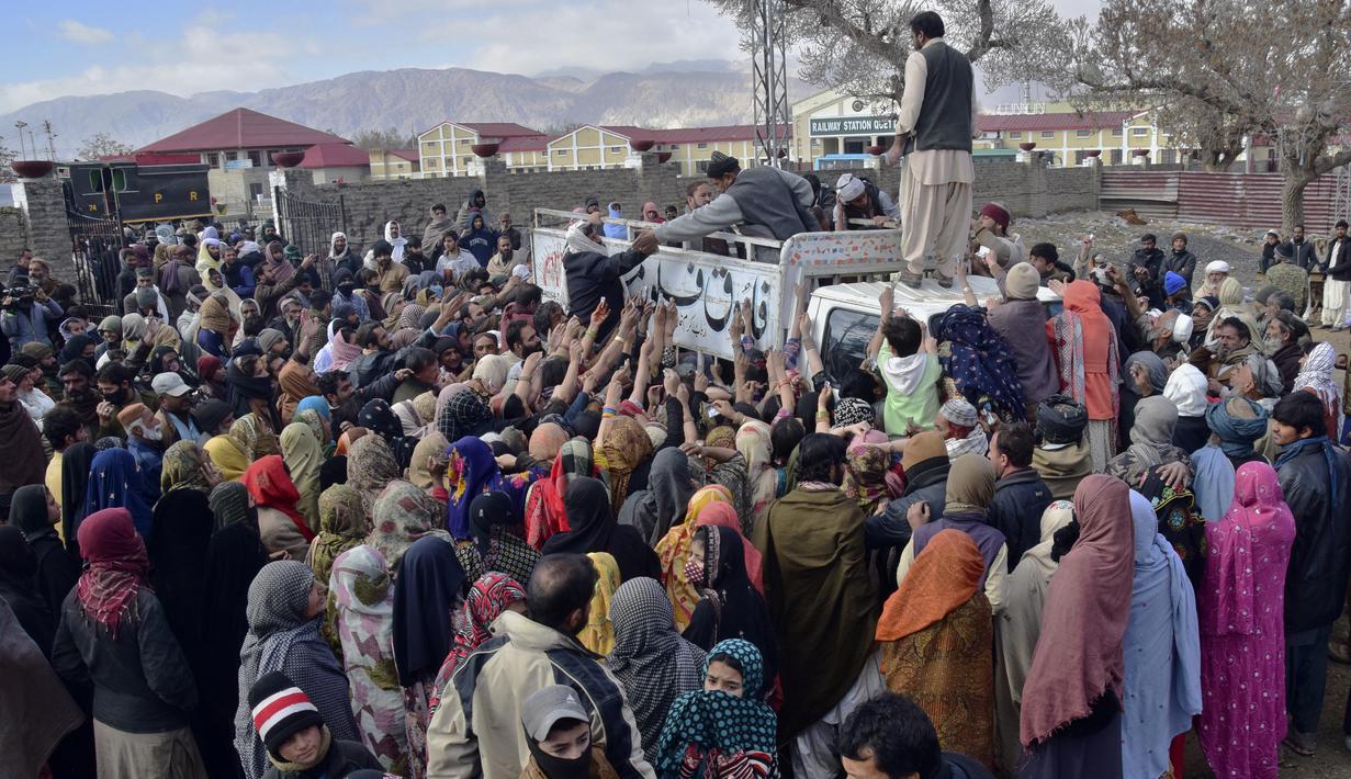 Orang-orang berdesak-desakan untuk membeli sekarung tepung terigu bersubsidi dari sebuah titik penjualan di Quetta, Pakistan, Kamis (12/1/2023). Orang-orang menderita akibat kenaikan harga tepung terigu di Pakistan baru-baru ini. (AP Photo/Arshad Butt)